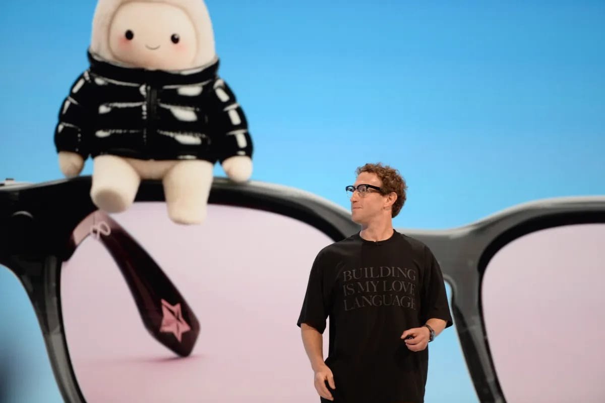 Meta Muse Spark Open launch: a presenter on stage in front of a giant pair of glasses with a plush mascot sitting on the frame
